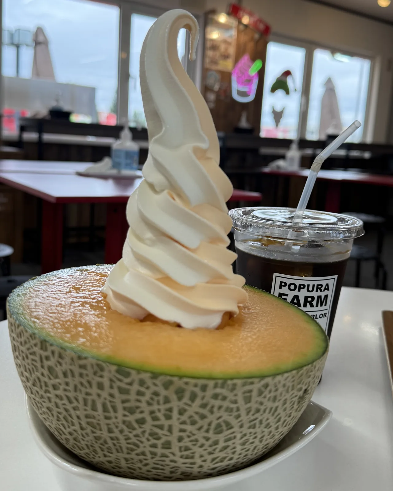 半顆哈密瓜上面擠了一大坨霜淇淋,旁邊是一杯冰咖啡