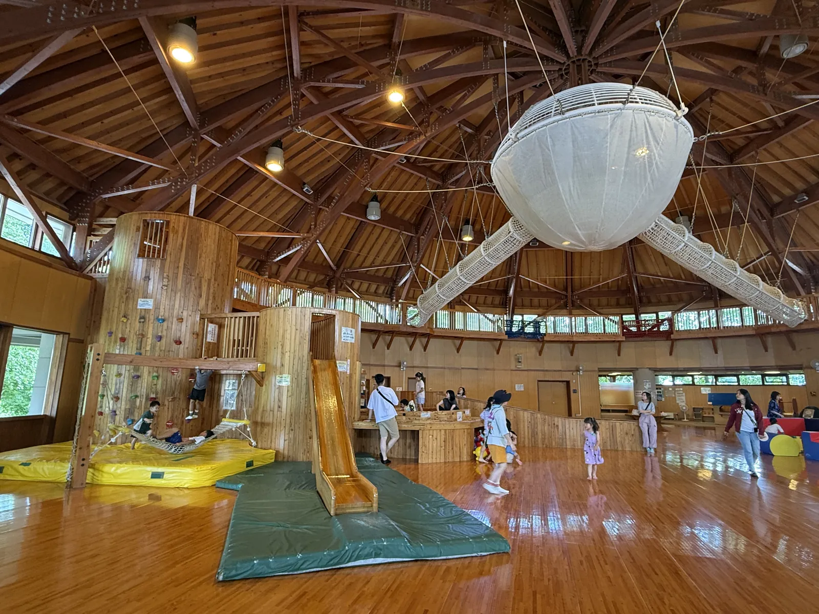 木造大廳的室內遊戲場,有攀岩牆、木頭溜滑梯,天花板吊著一顆大熱氣球